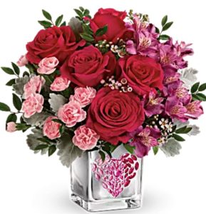 This vibrant arrangement includes hot pink roses, purple alstroemeria, light pink miniature carnations, pink waxflower, huckleberry, and dusty miller.
