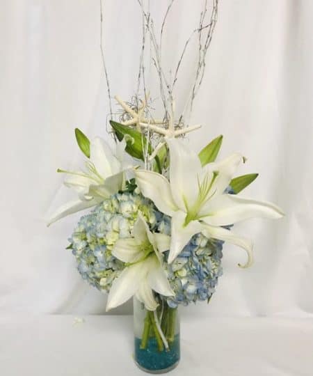 gorgeous design featuring fragrant star shaped lilies and blue hydrangeas supporting dancing sea stars.